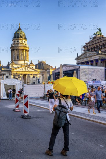 Man with a yellow umbrella standing at a barrier at Berlin's Gendarmenmarkt, Berlin, Germany