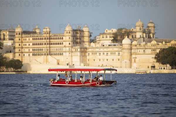 Excursion boat on Lake Pichola, behind the City Palace in the evening light, Udaipur, Rajasthan,
