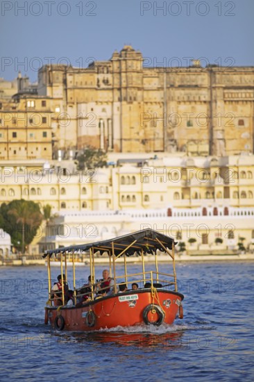 Electric excursion boat on Lake Pichola, behind the City Palace in the evening light, Udaipur,