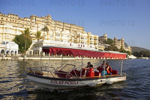 Excursion boat on Lake Pichola, behind the City Palace in the evening light, Udaipur, Rajasthan,