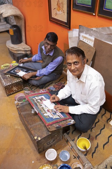 Miniature painters, 50 and 52 years old, painting pictures of the elephant and royal city palace in