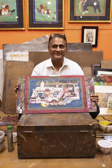 Miniature painter, 50 years old, shows a picture of the royal city palace in his studio, Udaipur,