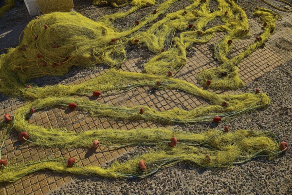 Yellow fishing nets spread on a stony ground on a sunny day, Agia Marina, Leros, Dodecanese, Greek