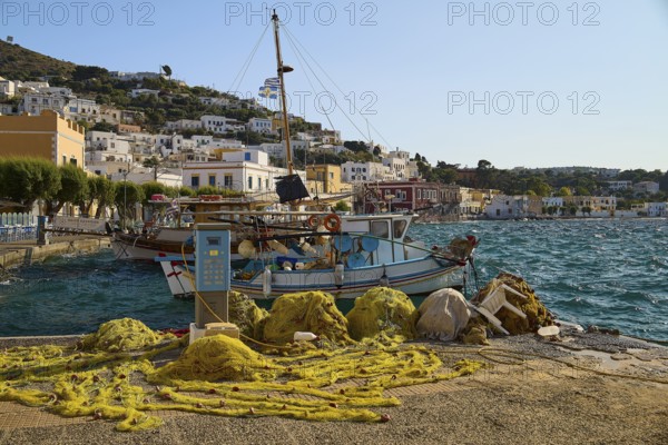 Fishing nets and boats at the harbour with a view of houses on the hillside, Agia Marina, Leros,
