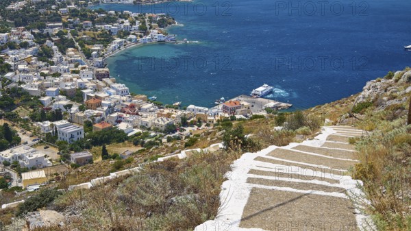 Ormos Alintas, stone path leads to a coastal village with bright blue sea and deep blue sky, Agia