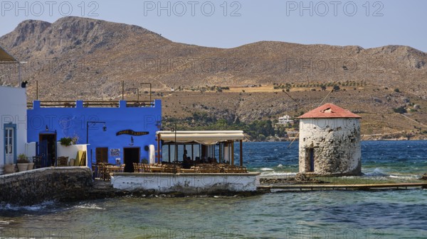 Restaurant Mylos, coastal landscape with blue buildings and a windmill by the sea, Agia Marina,