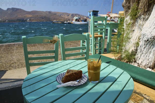 Cake and coffee on a green table by the sea, relaxing summer atmosphere with clear skies, Agia