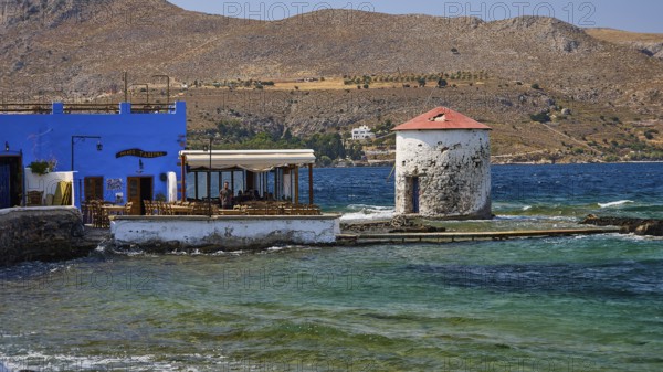 Restaurant Mylos, coastal village with windmill and blue buildings in front of mountain landscape,