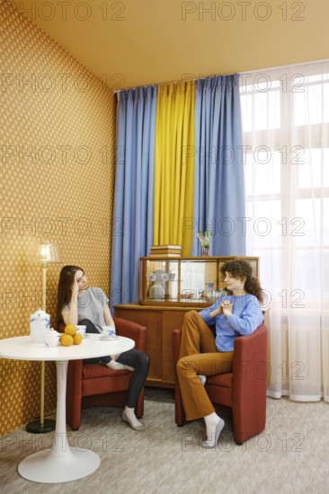 Two friends are sitting comfortably in a well-decorated living room and discussing their problems,