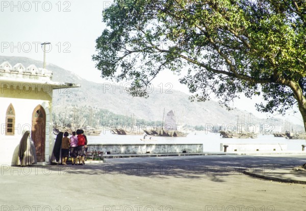Group women and nuns at quayside with Chinese junks in harbour, Macau, Asia 1964
