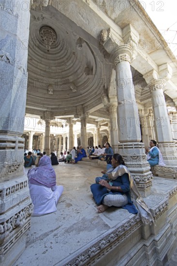 Indian woman praying between the white marble pillars in the Adinath temple in Ranakpur, Jain