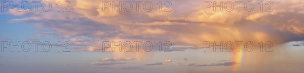 Background image for sky replacement, evening sky with illuminated clouds, rain shower and rainbow