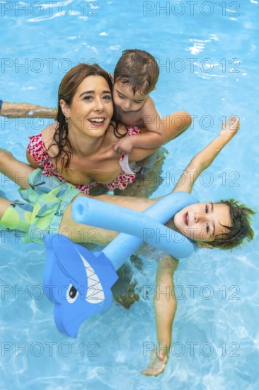 Happy family enjoying summer vacation, playing with inflatable toys in a refreshing blue swimming