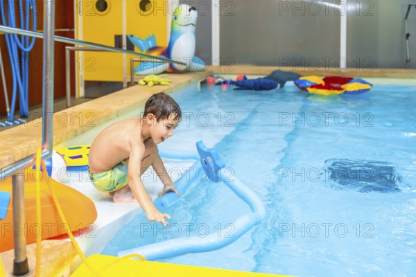 Boy enjoying playful moments with a colorful pool noodle float in an indoor swimming pool,