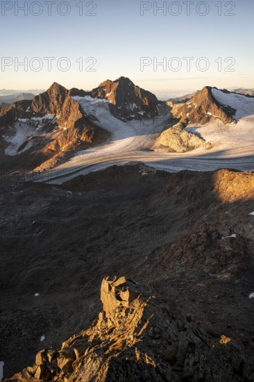 Picturesque high mountain landscape at sunrise with alpenglow, glacier and rocky mountain peaks in