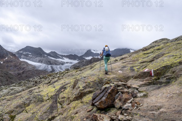 Mountaineer on hiking trail in high mountain landscape, view of glacier tongue of the
