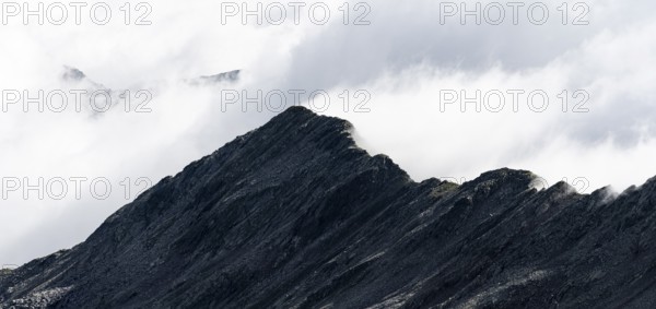 Mountain ridge with summit Zunderspitz and summit cross, cloudy, Stubai Alps, near Ridnaun, South