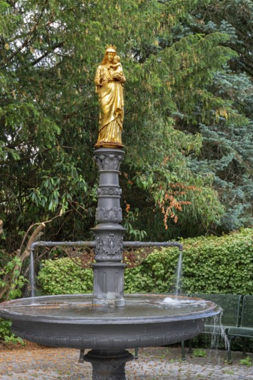 Fountain with a gilded statue of the Virgin Mary and baby Jesus, in front of St Briccius Church,