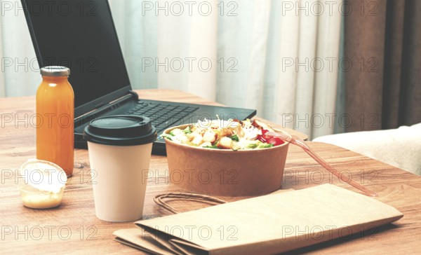 Work at home on a laptop, there is food on the table, salad, coffee and juice, delivery, there are
