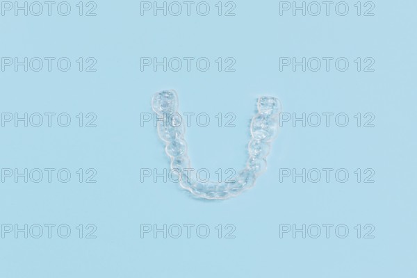 Top view of customized transparent dental teeth bite guard clear aligners for lower jaw on blue