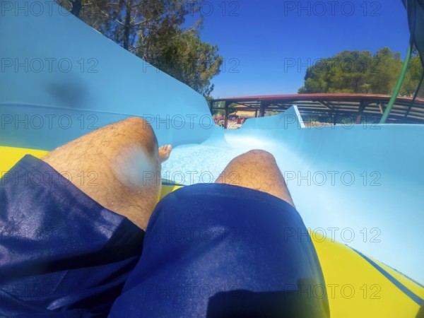 Point of view of a man sliding down a thrilling waterslide at an aquatic park, enjoying summer