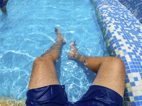 Man relaxing in a blue swimming pool, enjoying the refreshing water on a sunny summer day,