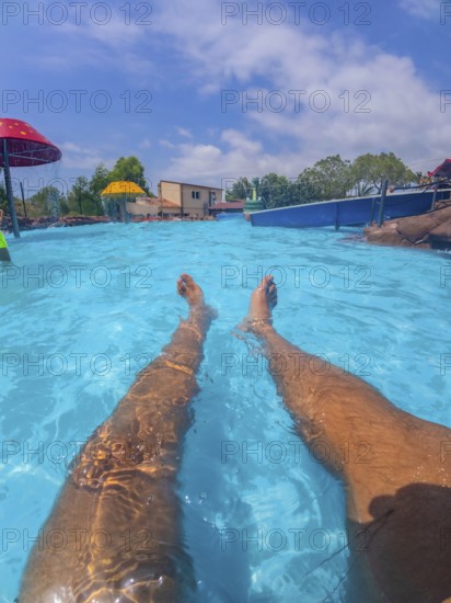 Pov shot of a man relaxing in a swimming pool at a water park, enjoying the summer sun and the