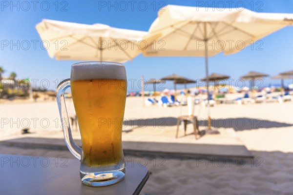 Cold beer glass sits on a table at a beach resort, offering a refreshing escape under the summer