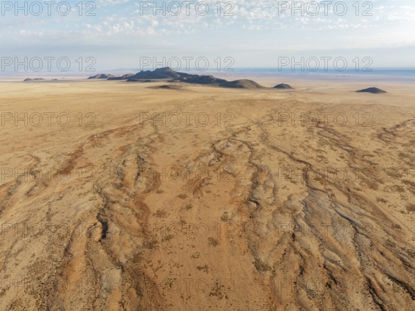 Dried-up river beds and isolated mountain ridges at the edge of the Namib Desert. Aerial view.
