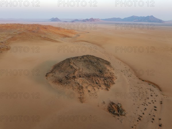 Arid plains, sand dunes and bare mountain ridges at the edge of the Namib Desert. Aerial view.