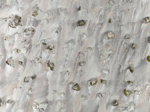 Small sand heaps form around the sparse vegetation in the Namib Desert. Aerial view. Drone shot.