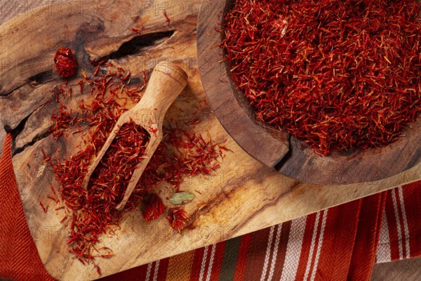 Spice saffron threads, in a wooden bowl, on a wooden table, top view, close-up