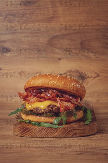 Burger with beef and bacon, with arugula and caramelized onions, pickles, sauce, homemade, no