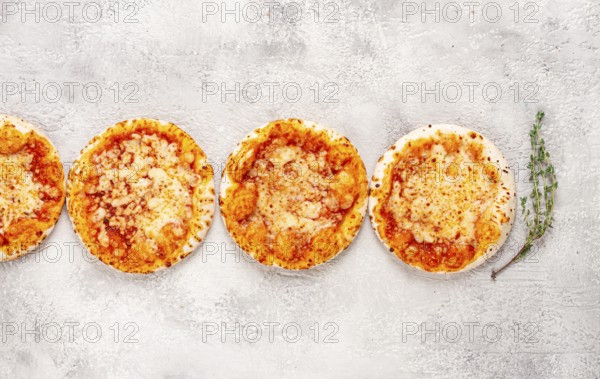 Four pizzetta Margaritas, on a light grey surface, top view