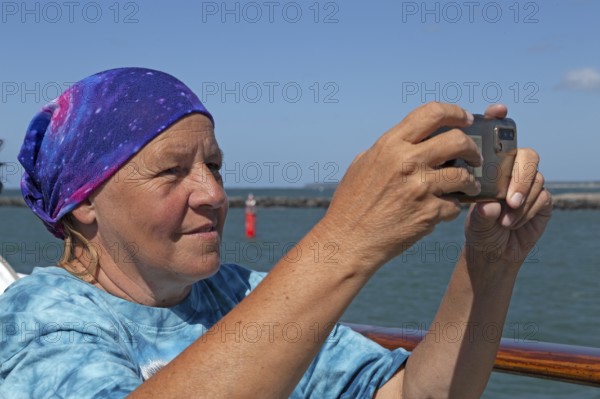 Elderly woman taking photos with smartphone, Warnemünde, Rostock, Mecklenburg-Western Pomerania,