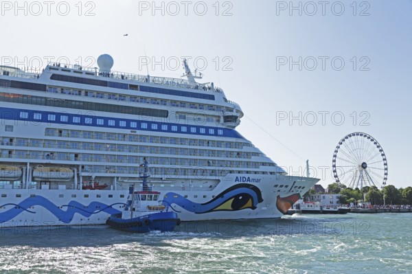 Cruise ship AIDA nova is pressed against quay wall by tugboat, Ferris wheel, Warnow, Warnemünde,