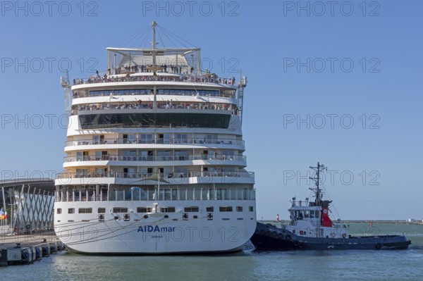 Cruise ship AIDA nova is pressed against quay wall by tugboat, Warnow, Warnemünde, Rostock,