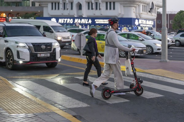 Man crossing a pedestrian crossing on an electric scooter, Abu Dhabi, United Arab Emirates