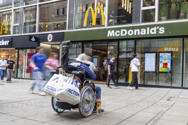 A man in a wheelchair in the Königstraße pedestrian zone in front of a branch of the McDonald's