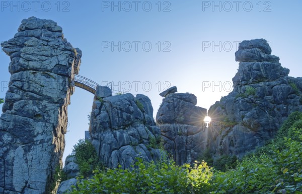 The morning sun shines through an opening in the Externsteine. The Externsteine, a sandstone rock