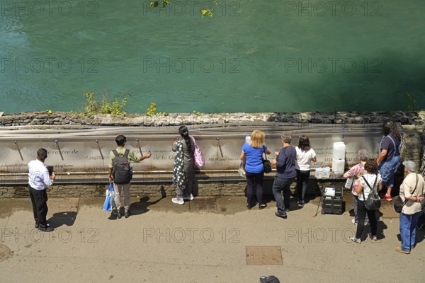 Pilgrims at the fountain with the holy water from the spring of the Marian pilgrimage site of