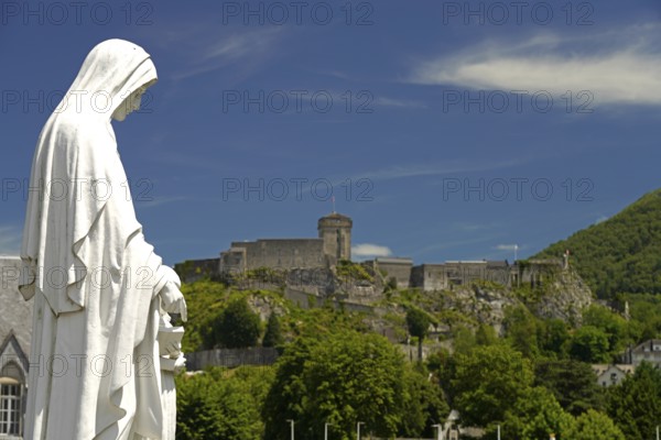 Statue on Rosary Square and the ChÃ¢teau fort de Lourdes fortress in the Marian pilgrimage town of