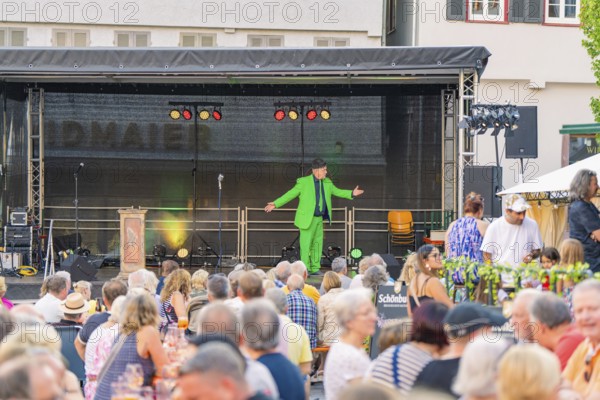 An entertainer on a stage entertains a large audience at an evening event, 950 years Weil der Stadt