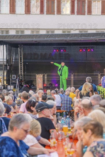 A man in a green suit stands on a stage and speaks to a large crowd, 950 years Weil der Stadt
