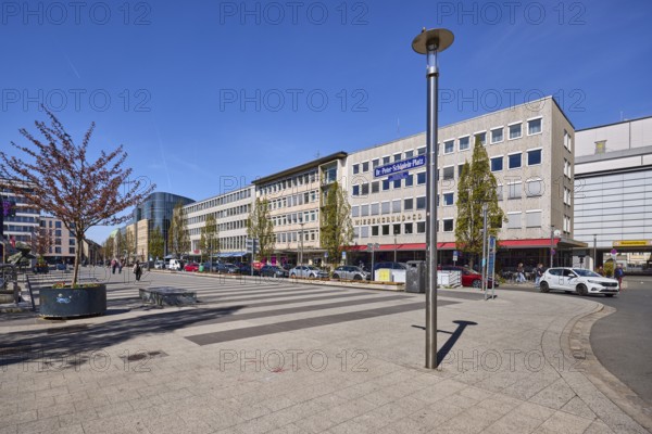 Square, lantern, modern architecture, trees, parking lane with vehicles, alleyway sign, blue sky,
