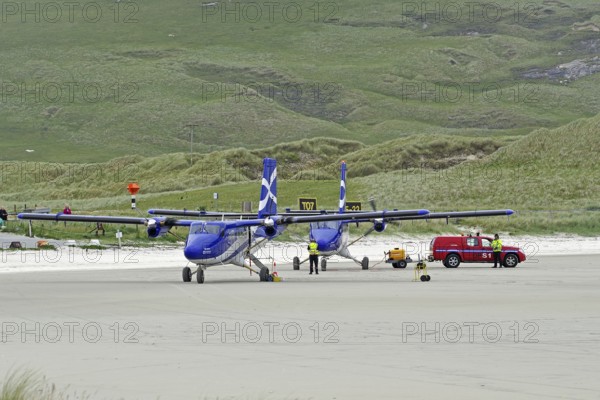 Aeroplanes standing on a runway in front of green hills, accompanied by a red vehicle, Outer