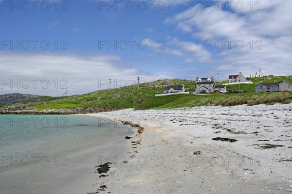 Quiet sandy beach with neighbouring houses under a slightly cloudy sky, Outer Hebrides, Eriksay,