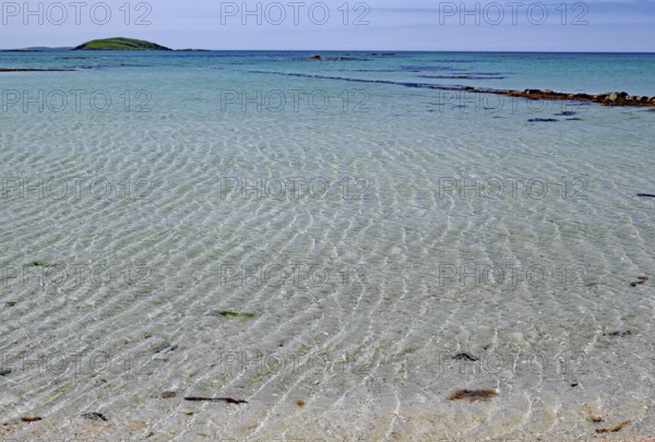 Clear bright blue beach with gentle waves under a cloudless sky, Outer Hebrides, Eriksay, Scotland,