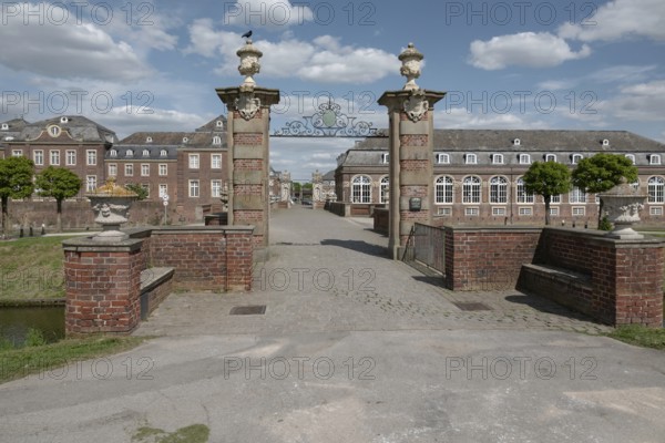 Large brick building with Tor tor and decorated pillars under a blue sky, moated castle