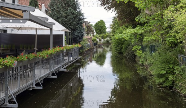 River with adjoining terrace and flowers, surrounded by green vegetation, Borken-Gemen,